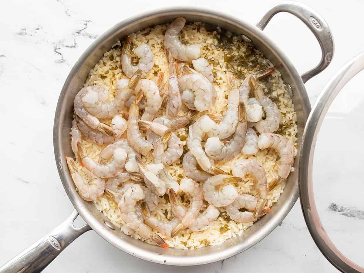 raw shrimp added to the rice in the skillet