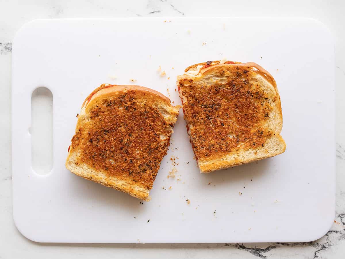 pizza melt cut in half on a cutting board