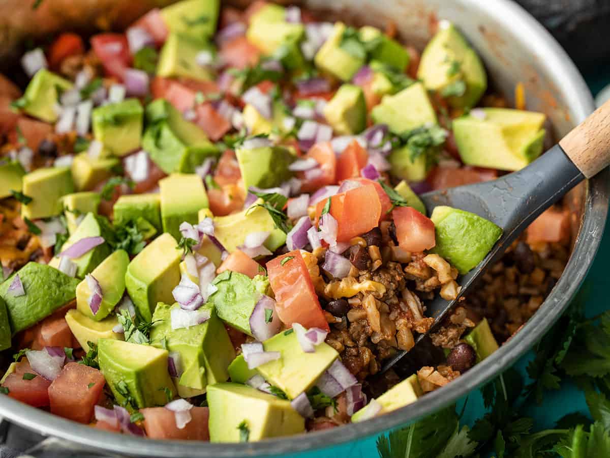 Close up side view of beef and cauliflower taco skillet being scooped out of the skillet