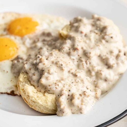 Side view of biscuits and gravy on a plate with eggs