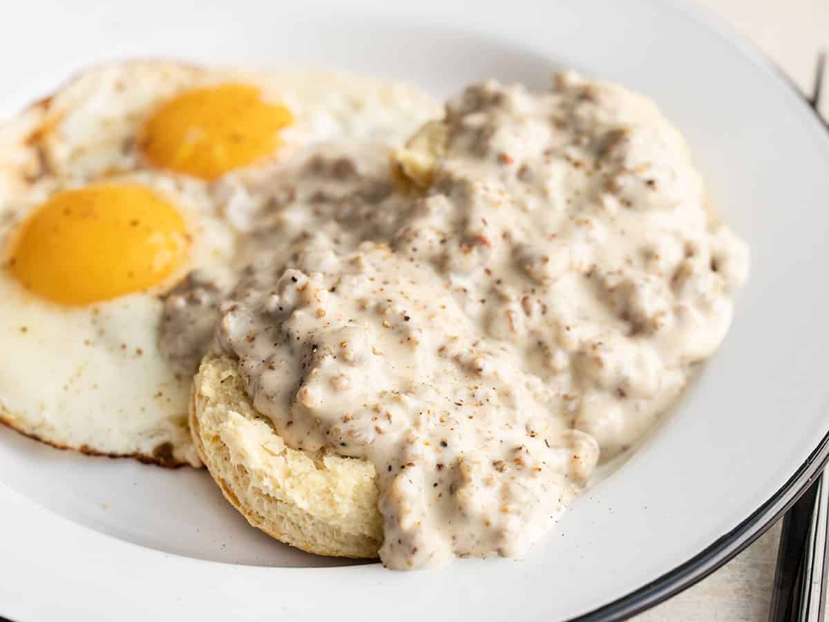 Side view of biscuits and gravy on a plate with eggs