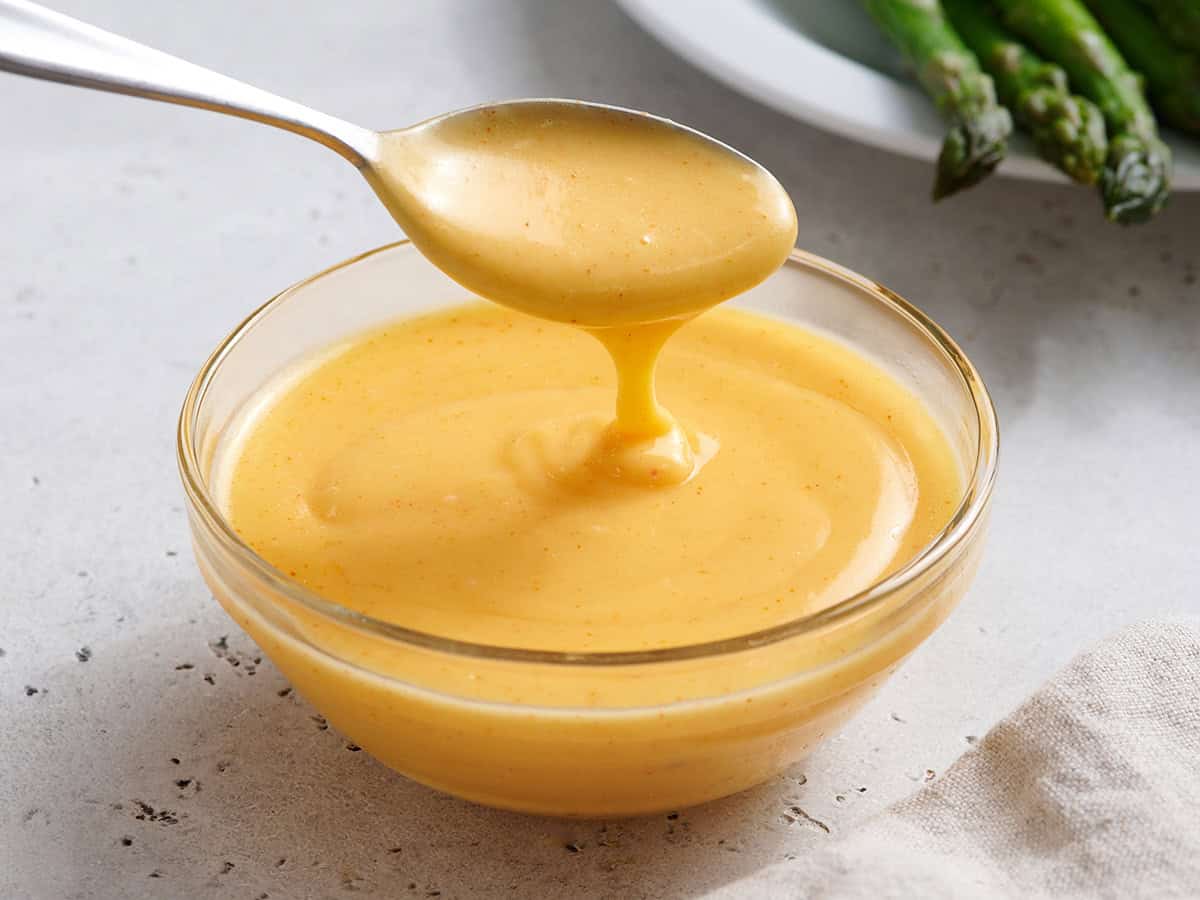 Homemade hollandaise sauce in a bowl with a spoon.