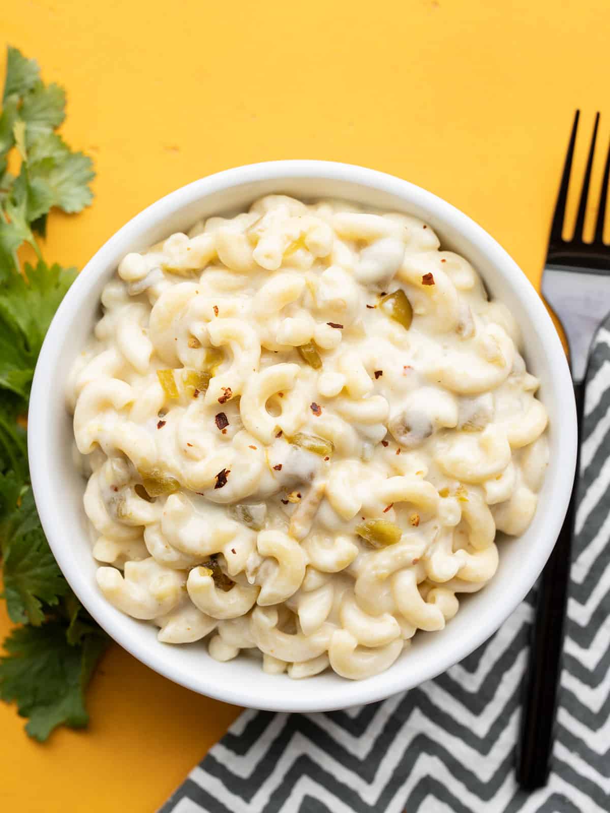 overhead view of green chile mac and cheese in a bowl with a fork on the side