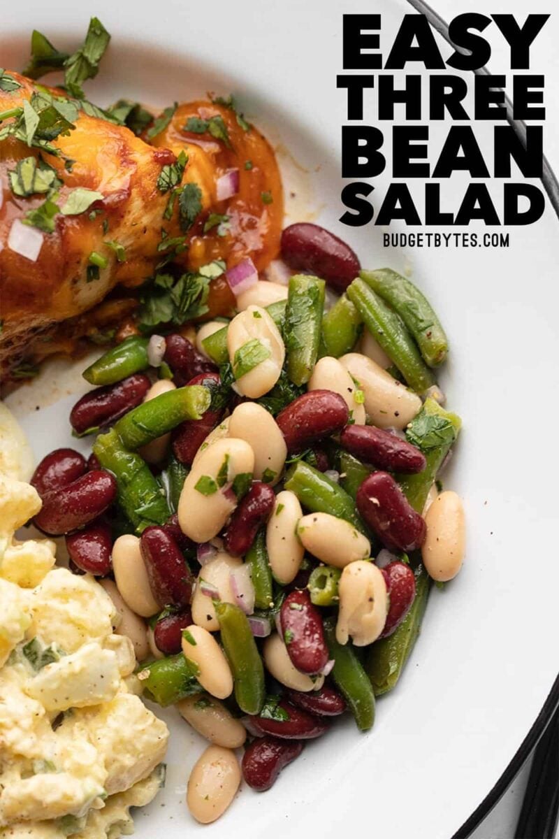 three bean salad on a plate with chicken and potato salad