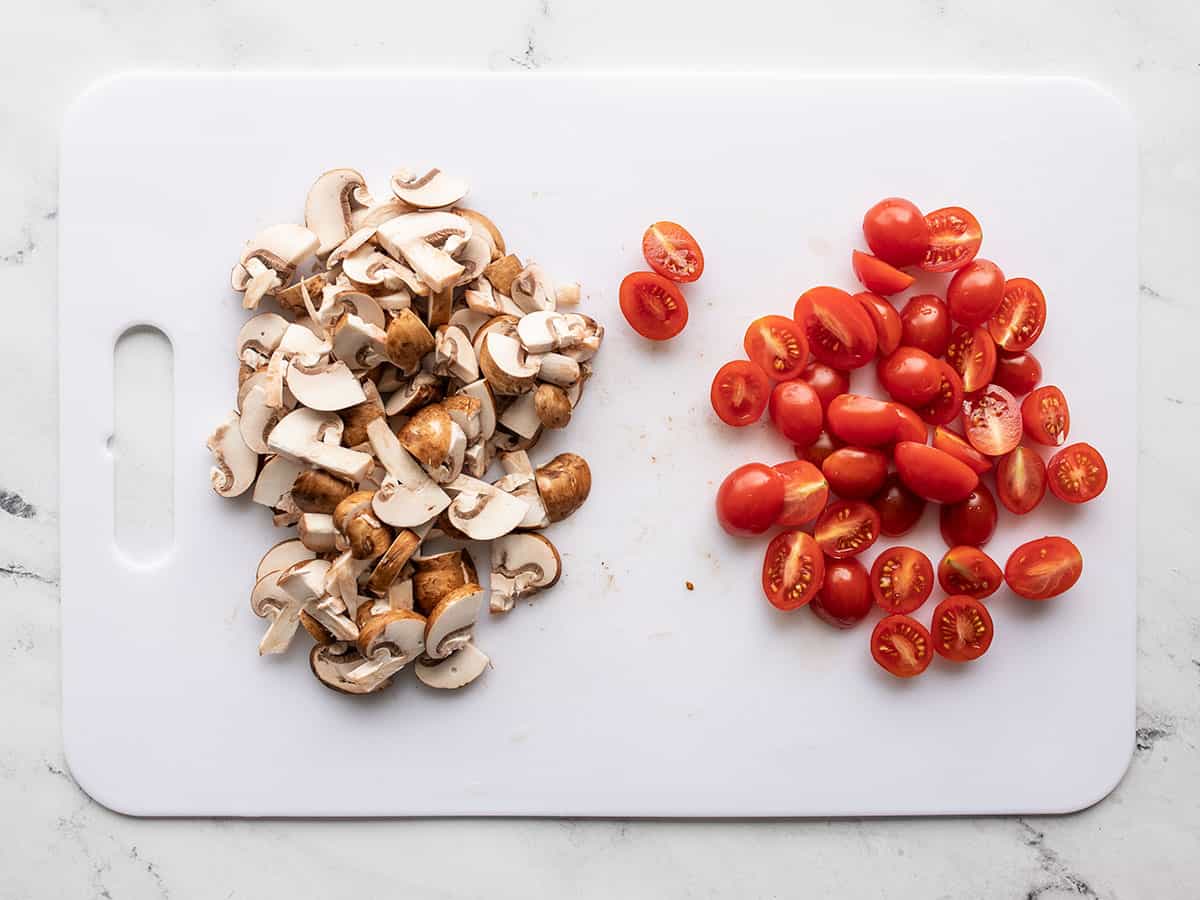Sliced mushrooms and tomatoes on a cutting board