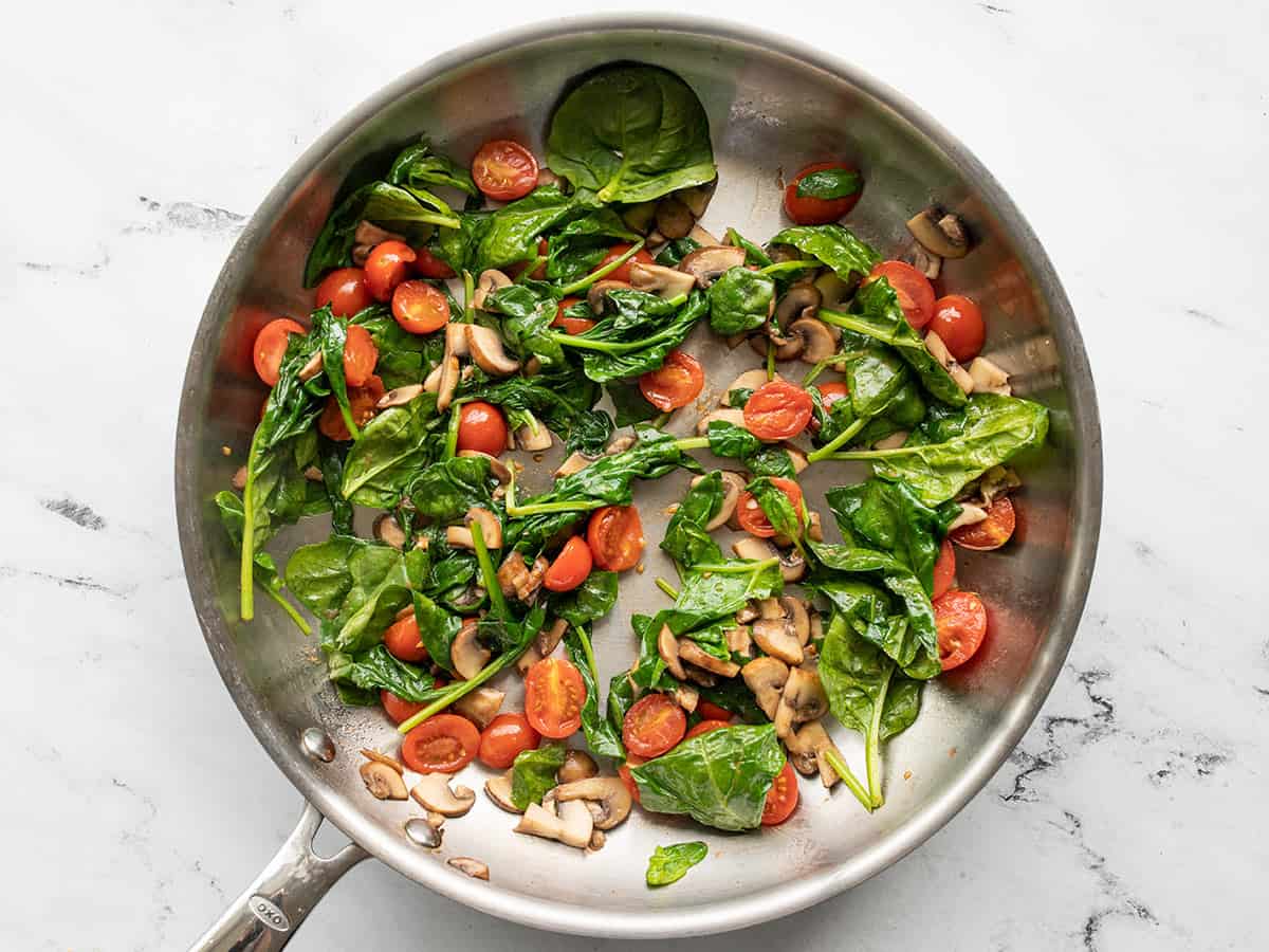 spinach added to the skillet with tomatoes and mushrooms