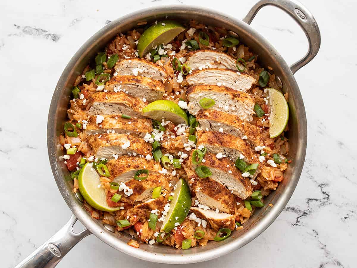 Chipotle lime chicken and rice garnished with cotija, green onion, and limes