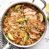 Chipotle lime chicken and rice in the skillet garnished with limes