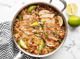 Chipotle lime chicken and rice in the skillet garnished with limes
