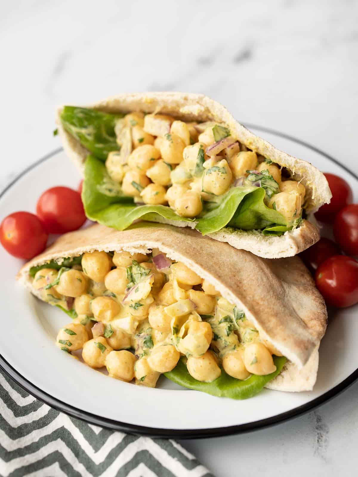 Curry Chickpea Salad stuffed into a pita on a plate with grape tomatoes