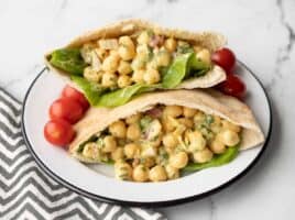 two pita pockets stuffed with curry chickpea salad on a plate with grape tomatoes