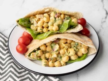 two pita pockets stuffed with curry chickpea salad on a plate with grape tomatoes