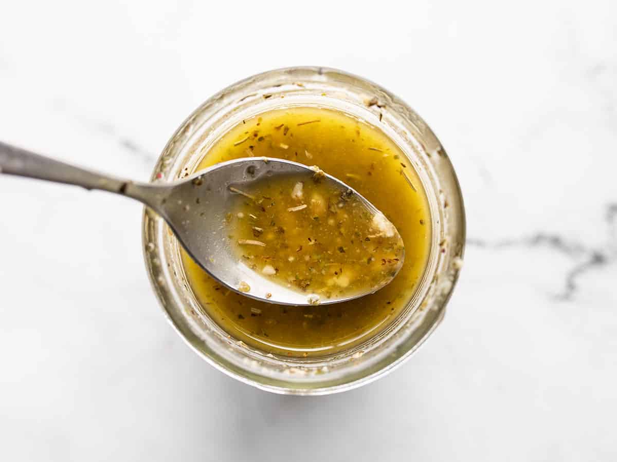 Overhead view of a spoon in a jar full of homemade italian dressing