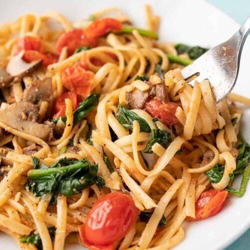 Side view of quick veggie pasta in a bowl twirled around a fork