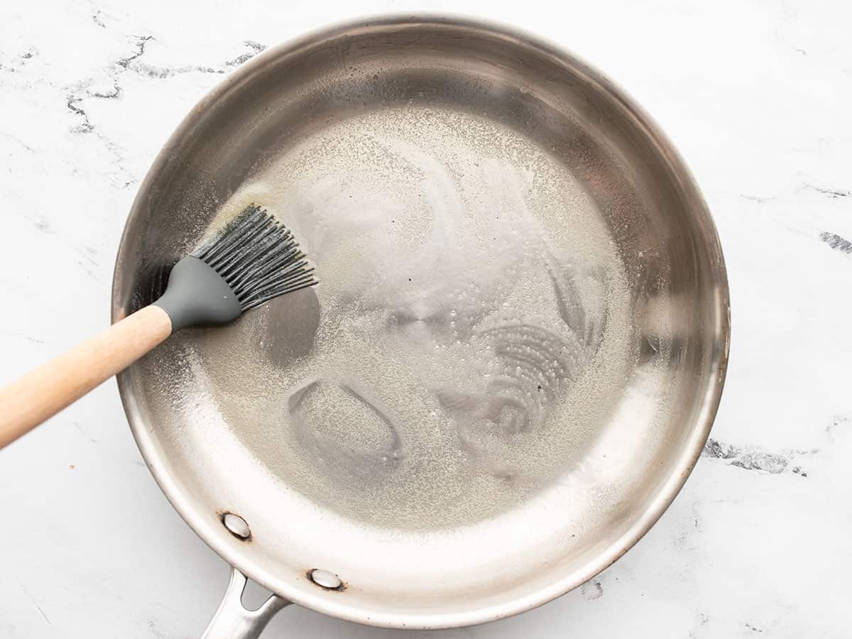 melted butter being brushed over the inside of a skillet