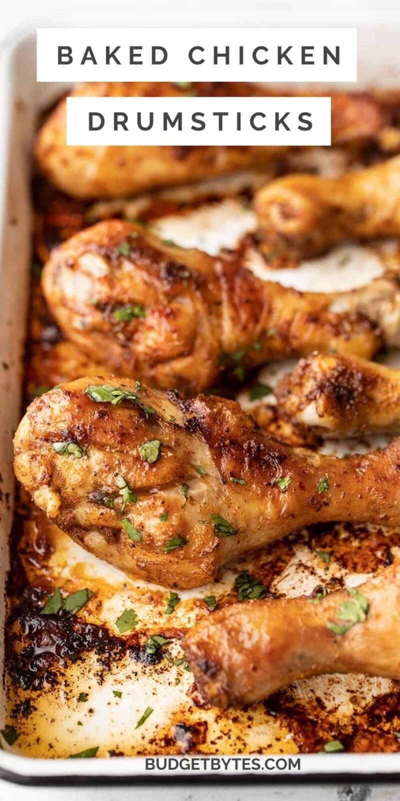 Close up of baked chicken drumsticks on a baking sheet, title text at the top