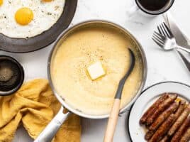 a pot of cheese grits surrounded by other breakfast items
