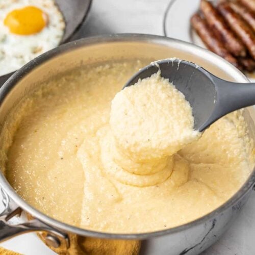 Cheese grits dripping off the serving spoon into the pot