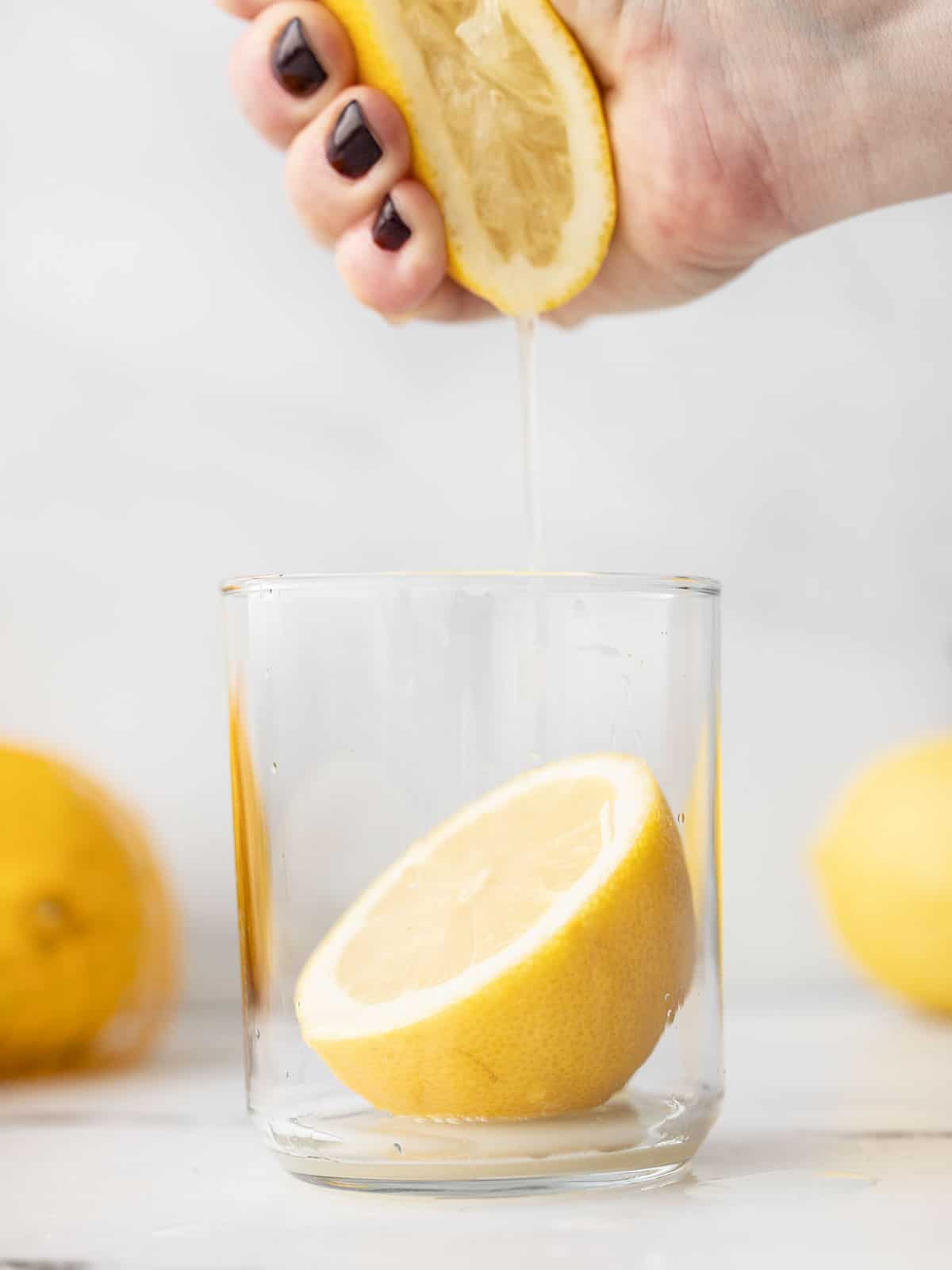 A hand squeezing a lemon into a glass