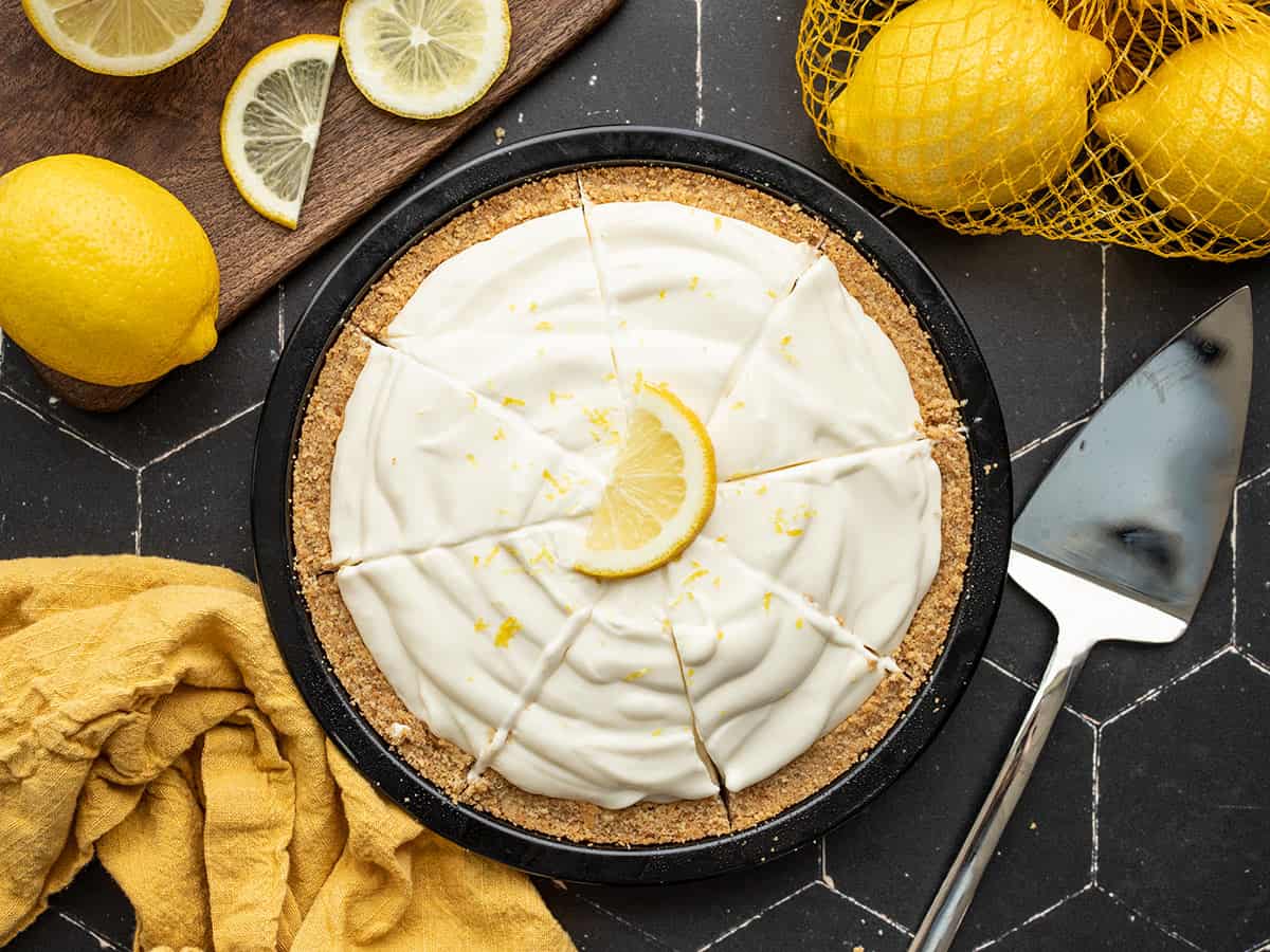 Top view of a sliced ​​lemon cream cake with lemons on the sides