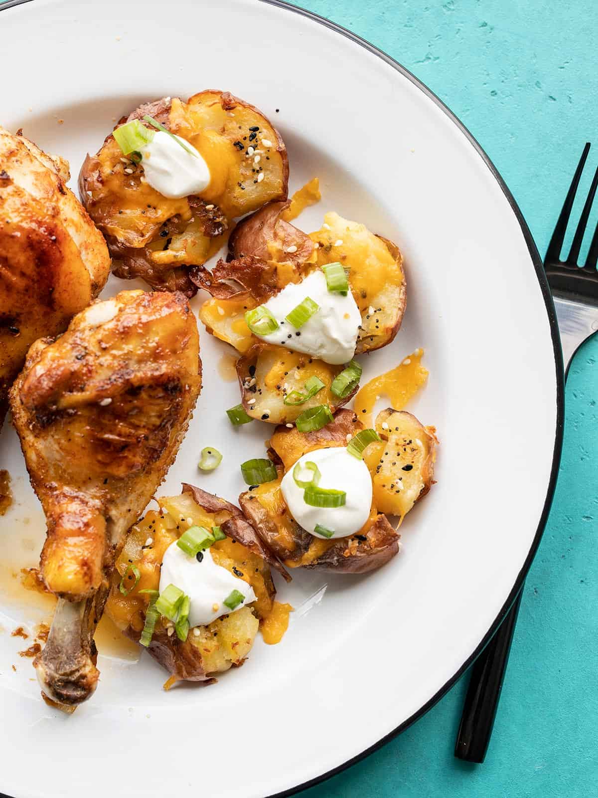 loaded smashed potatoes on a plate with a chicken drumstick