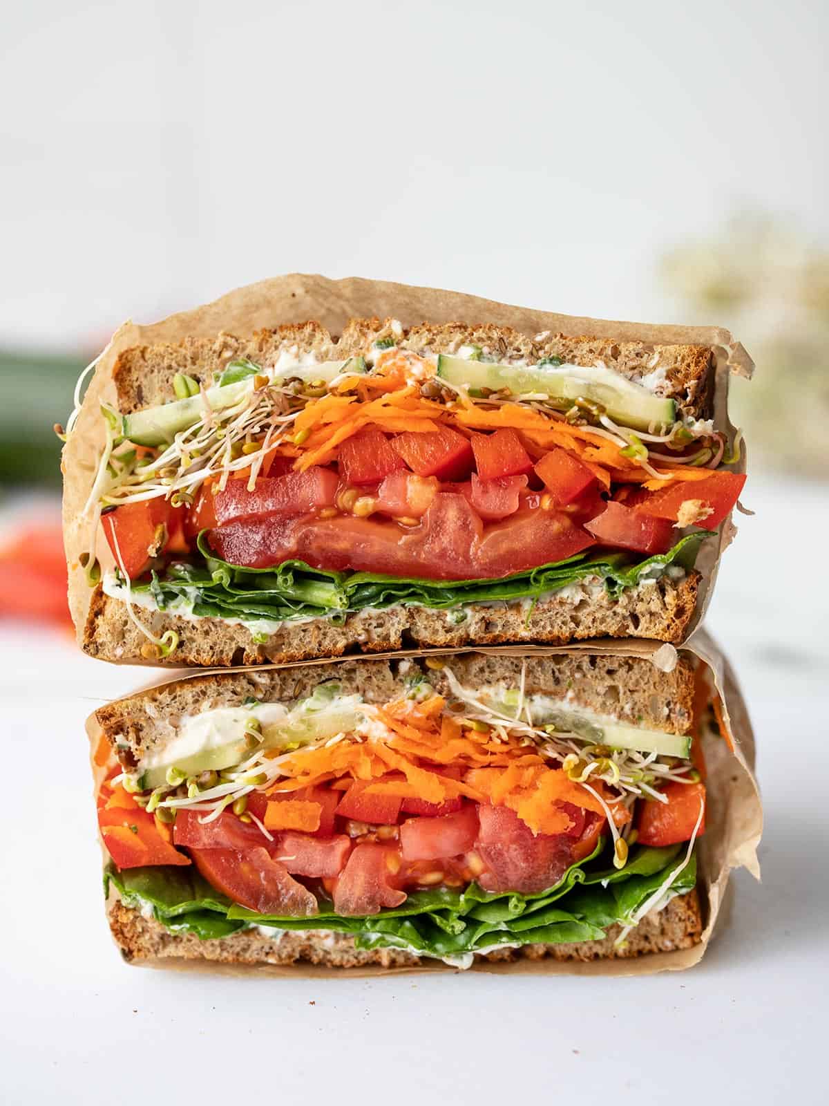 An ultimate veggie sandwich cut in half and stacked, cut sides facing the camera