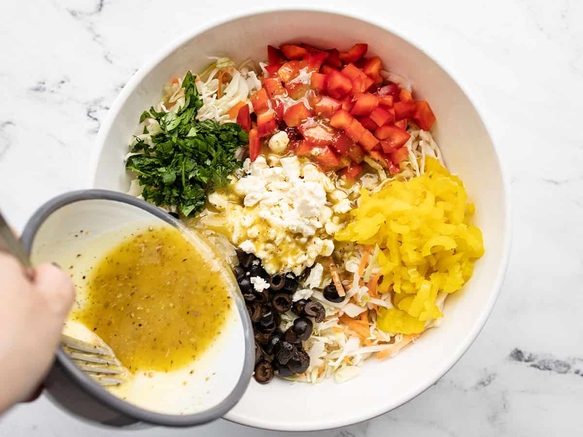 Lemon garlic vinaigrette being poured over salad ingredients