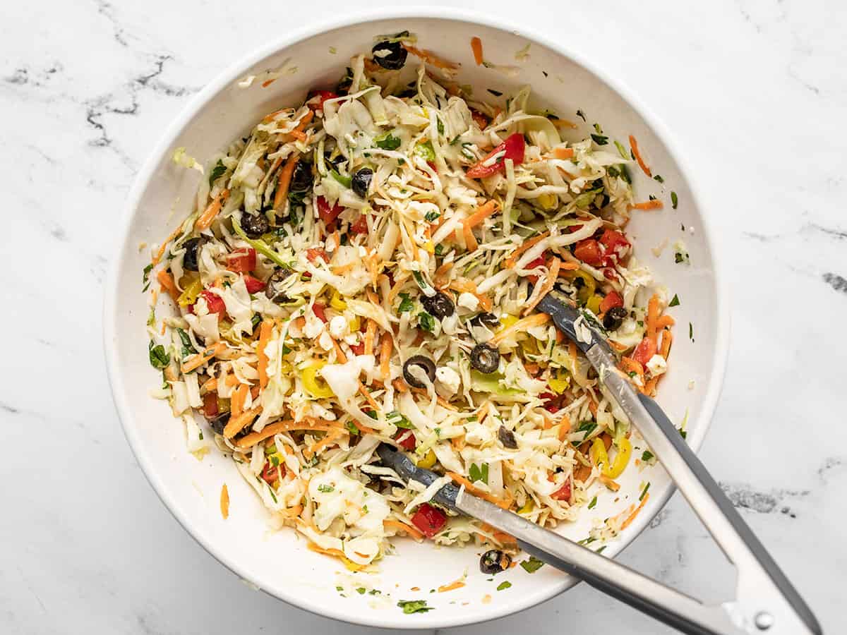 Finished mediterranean coleslaw in a bowl with tongs