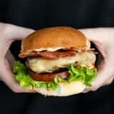 Close up side view of a ranch turkey burger held in hands