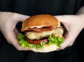 Close up side view of a ranch turkey burger held in hands