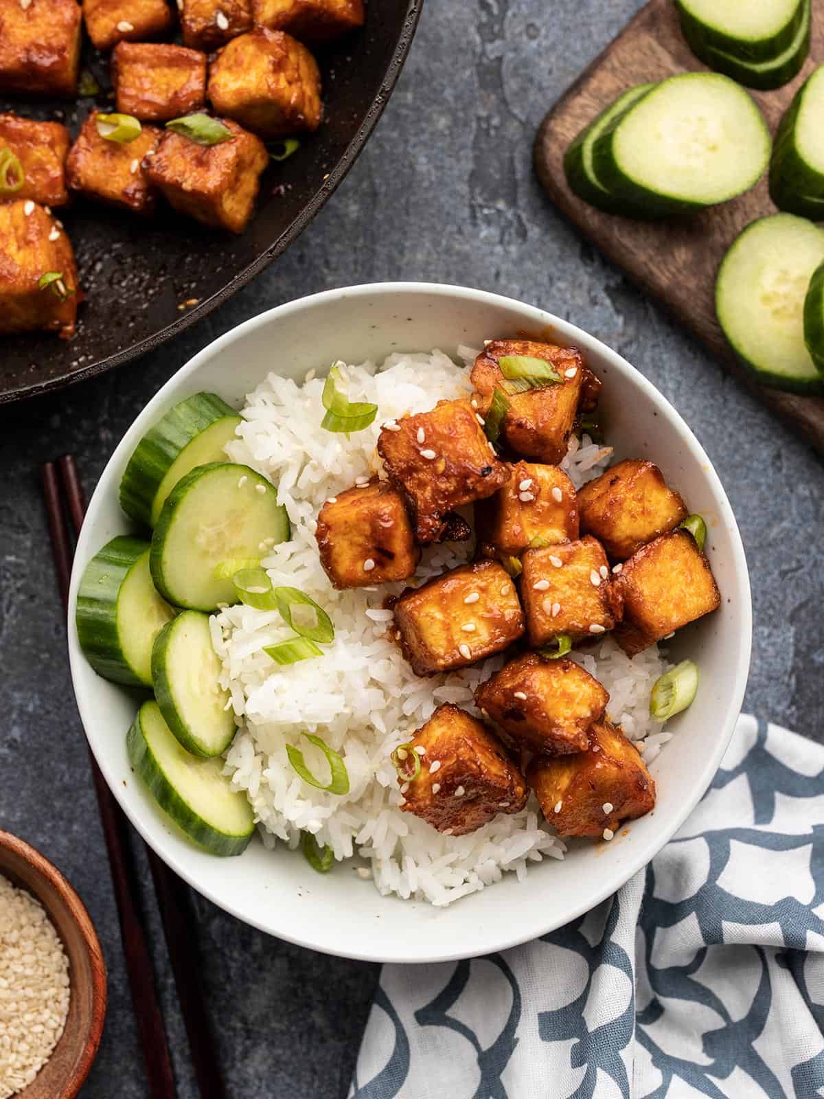 honey sriracha tofu in a bowl with rice and cucumber