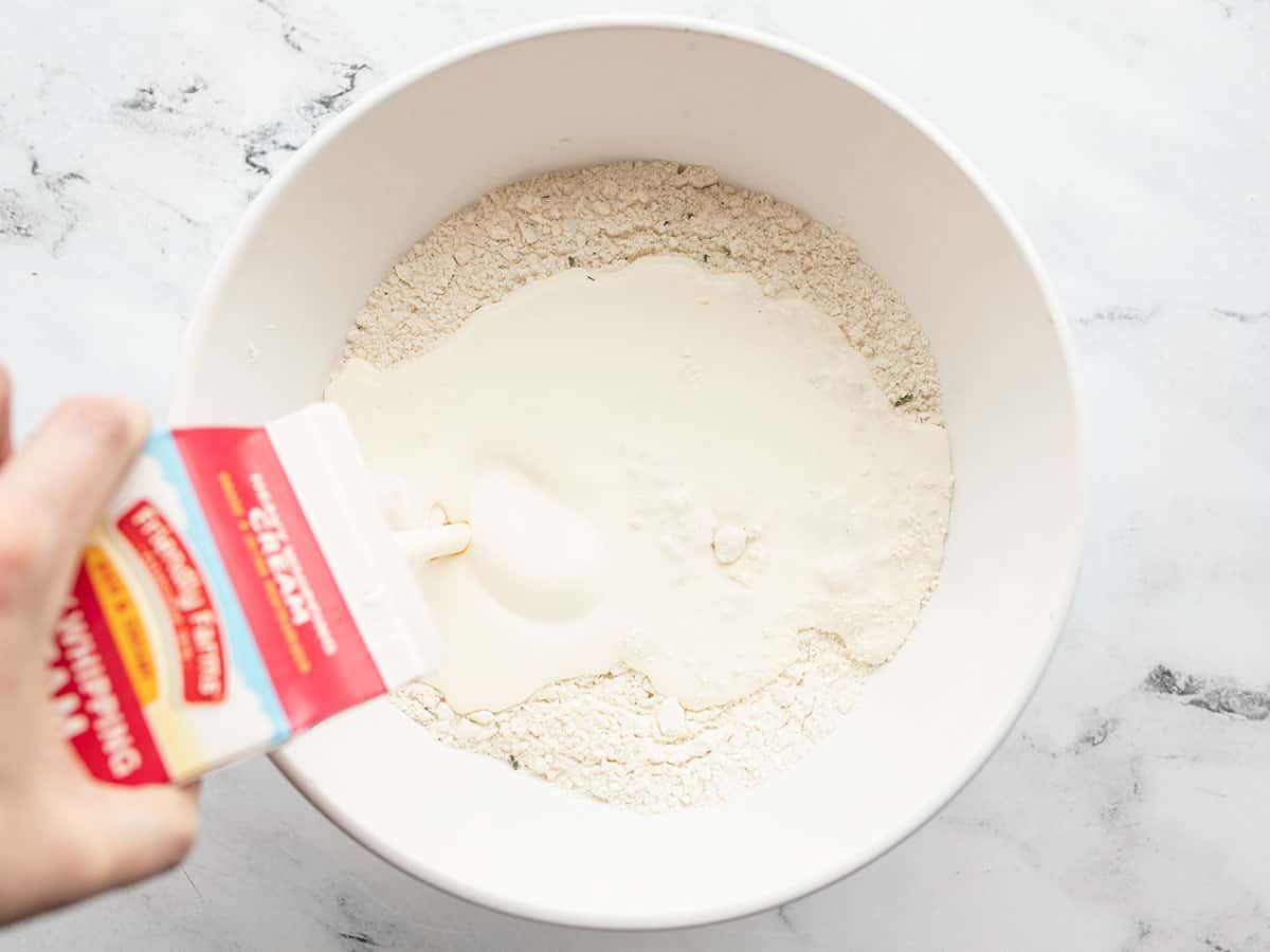 heavy cream being poured into the dry ingredients