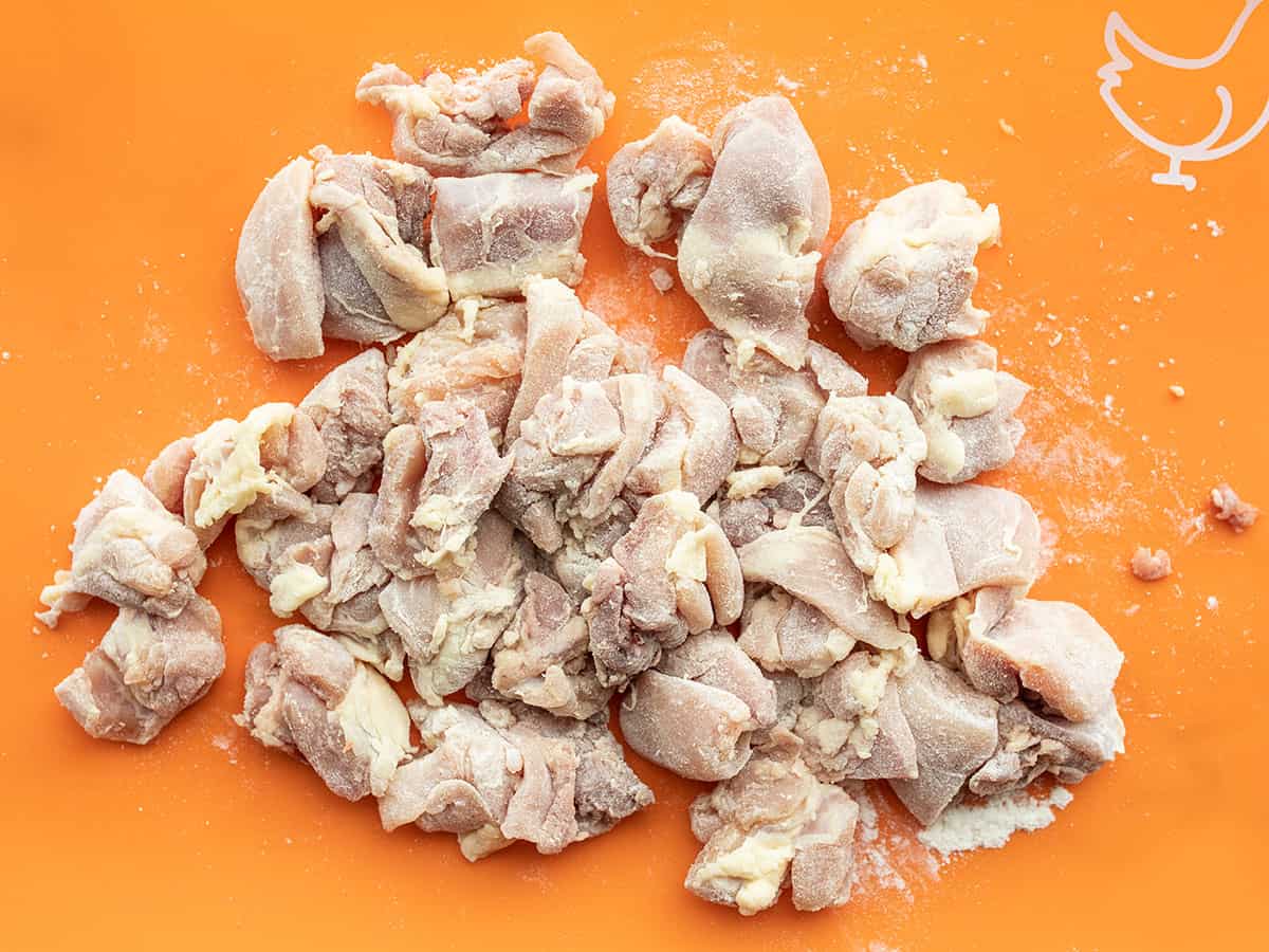 Flour coated chicken thigh pieces on a cutting board