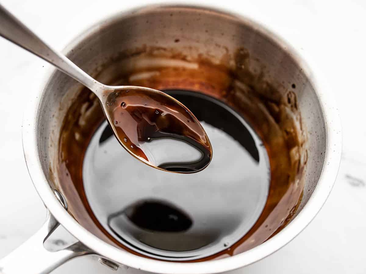 Finished balsamic glaze on a spoon over the pot