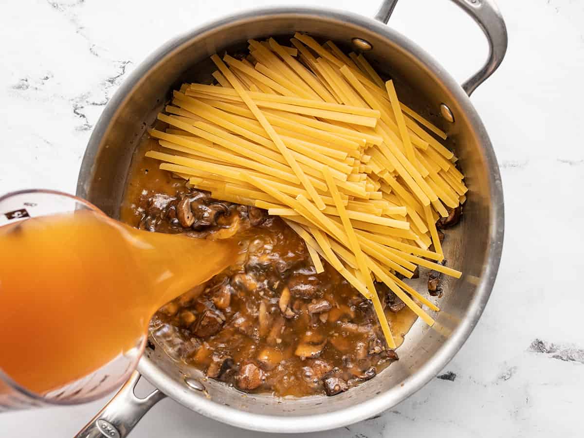 fettuccine in the skillet, broth being poured in