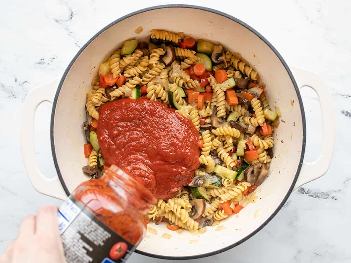 Pasta sauce being poured into the pot