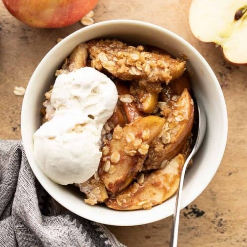 Apple crisp in a bowl topped with vanilla ice cream