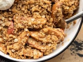 close up of apple crisp being scooped out of the baking dish