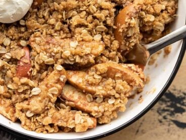 close up of apple crisp being scooped out of the baking dish