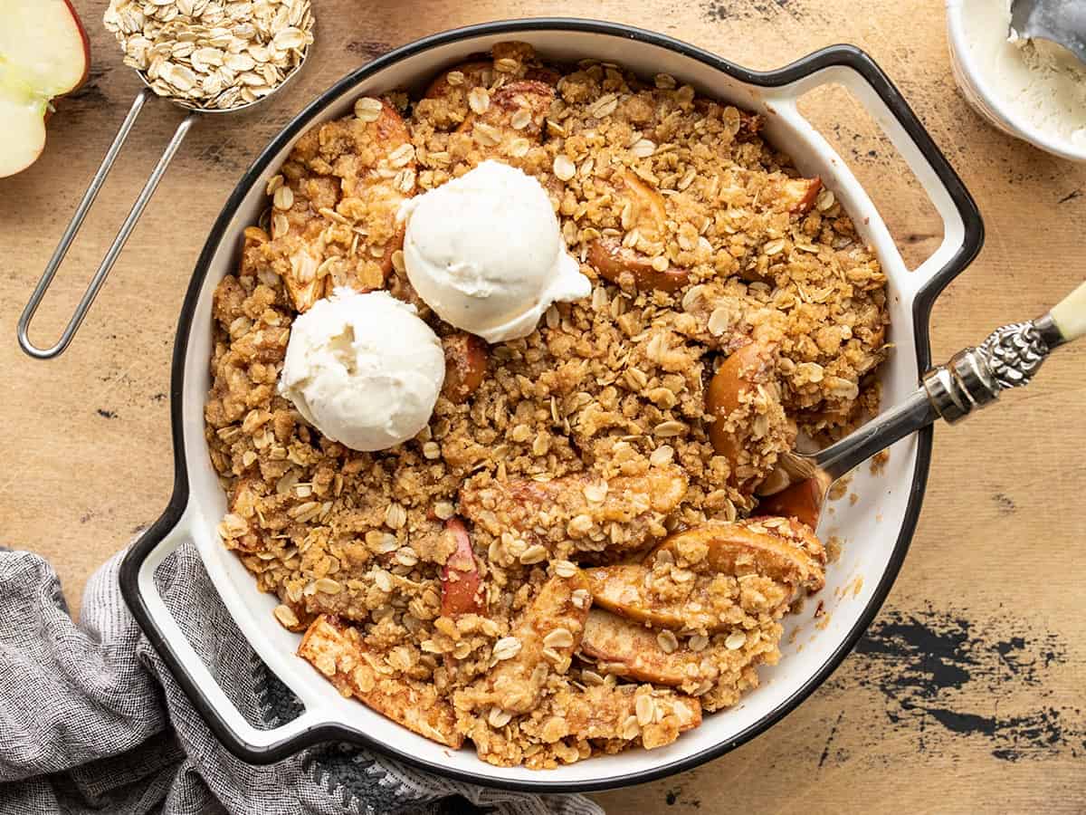 Overhead view of apple crisp in the baking dish with two scoops of ice cream