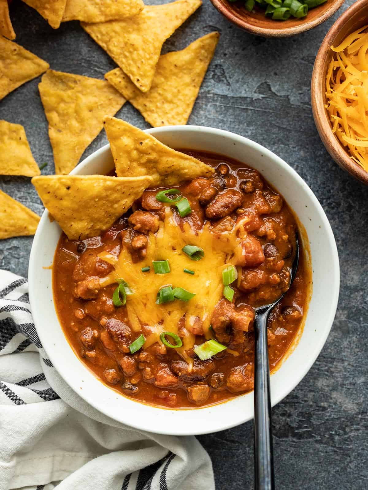 A bowl of pumpkin chili with cheese and tortilla chips