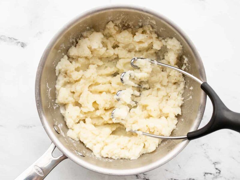 Mashed potatoes in the pot with a potato masher