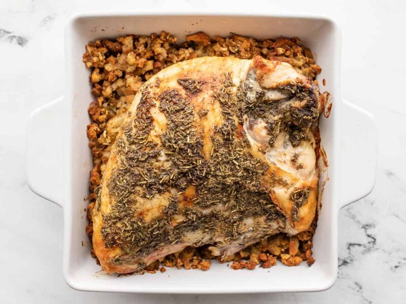 Roasted turkey breas in a casserole dish on top of stuffing