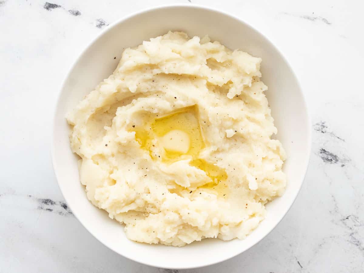 mashed potatoes in a bowl with melted butter on top