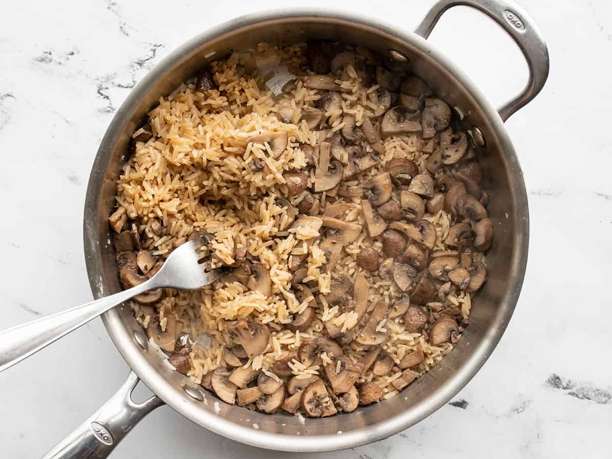Mushroom rice being fluffed with a fork