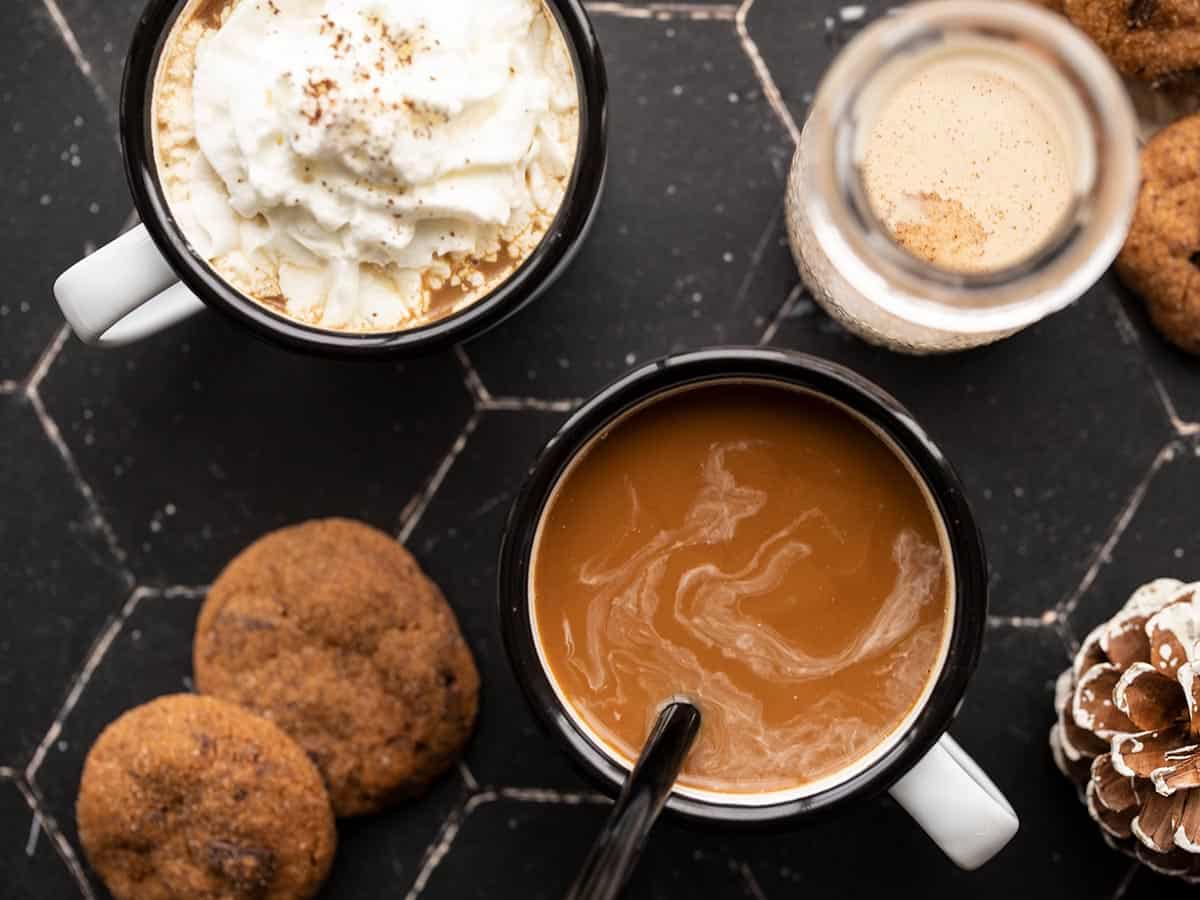 Two mugs of coffee from above, a bottle of creamer on the side