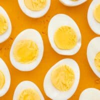 several halved hard boiled eggs against a yellow background