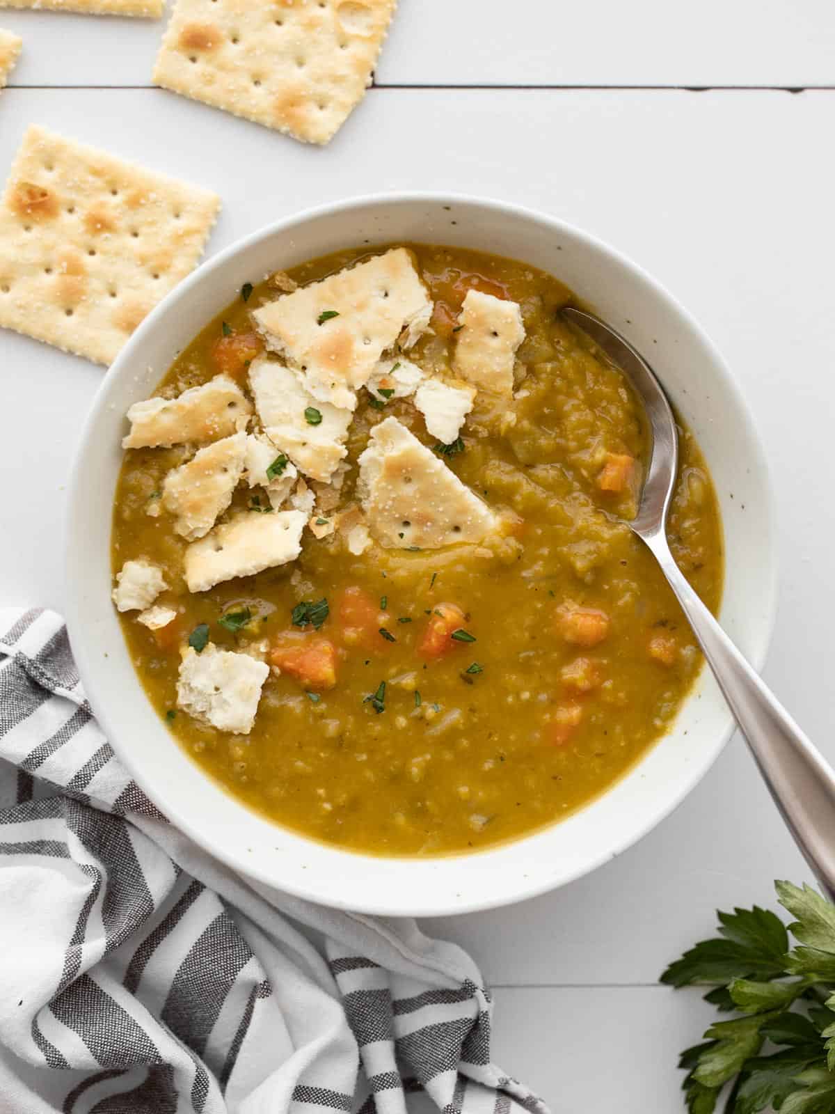 Overhead view of a bowl of split pea soup with saltine crackers