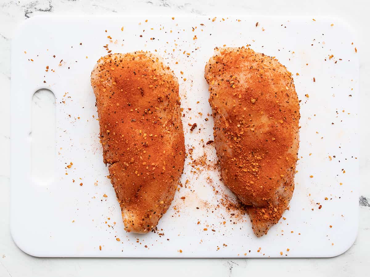 Seasoned chicken breasts on a cutting board