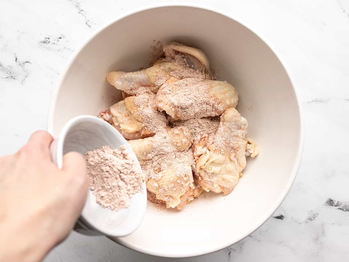 Seasoning being sprinkled over the chicken wings